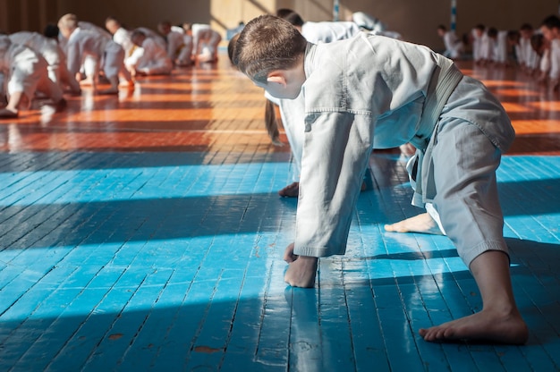 Kinderen trainen op karatedo Jonge atleten karateka's warmen en strekken zich uit in de sportschool op een houten vloer Banner met ruimte voor tekst Foto zonder gezichten