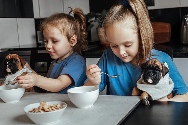 Kinderen twee meisjes voeden kleine puppy's met hun ontbijt