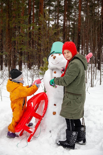 Kinderen van negen en drie jaar oud op winterwandeling in de buurt van sneeuwpop