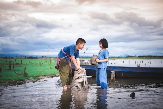 Kinderen vangen vis en hebben plezier in het kanaal. Levensstijl van kinderen op het platteland van Thailand.