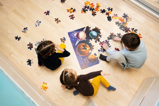 Kinderen verbinden puzzelstukjes in een kinderkamer op de vloer thuis Leuke gezinsactiviteit vrije tijd
