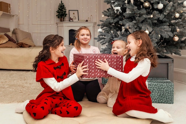 Kinderen verheugen zich over het nieuwjaarscadeau dat op de grond bij de kerstboom zit