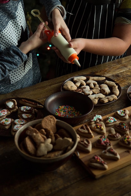 Kinderen versieren zelfgemaakte peperkoekkoekjes met slagroom en suikertopping Plat leggen