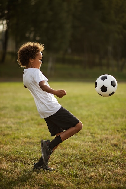 Foto kinderen voetballen onder toezicht van voetbaltrainer