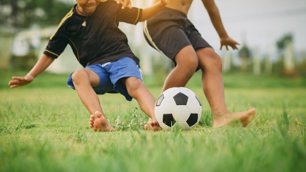 Kinderen voetballen voetbal om te oefenen op het groene grasveld