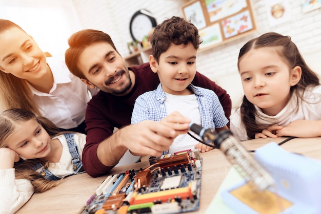 Kinderen werken samen met leerkracht met een soldeerbout.