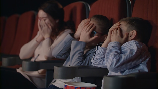 Kinderen zijn bang in de bioscoop. Bange kinderen bedekken gezichten met hun handen