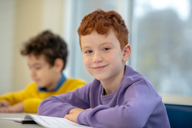 Kinderen zitten aan de schoolbank met klasgenoot