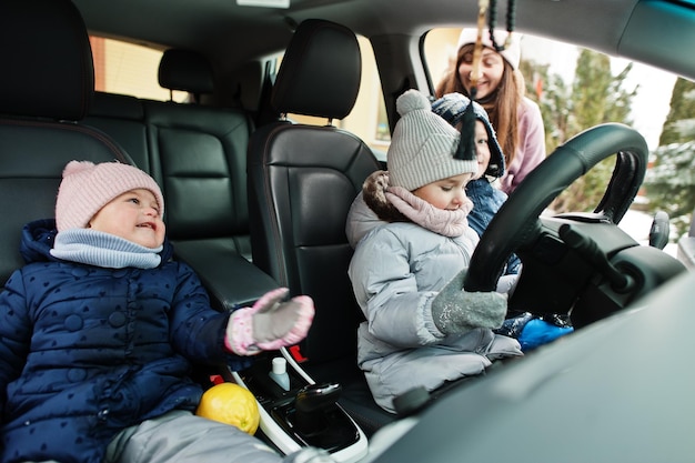 Kinderen zitten in de winter in een elektrische auto in de tuin van het huis