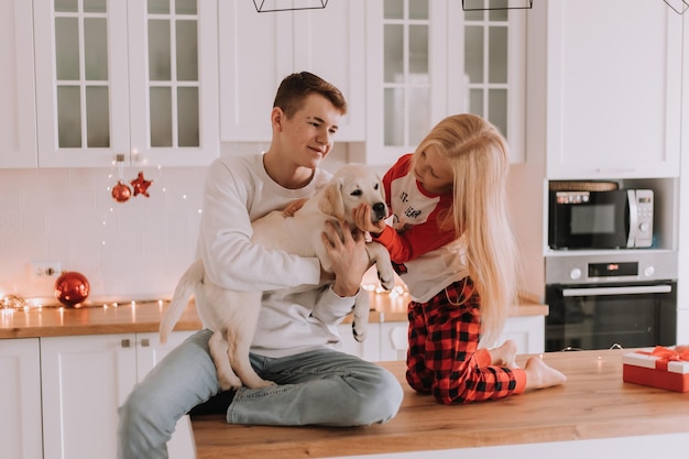 Kinderen zitten met hun geliefde hond in de kerstkeuken. familie tijdverdrijf. levensstijl. broer en zus, jongen en meisje spelen en dollen met een huisdier. ruimte voor tekst. Hoge kwaliteit foto