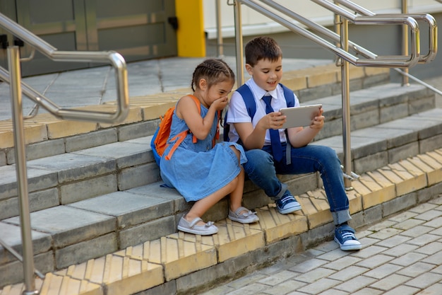 kinderen zittend op de trap terwijl ze op tablet kijken