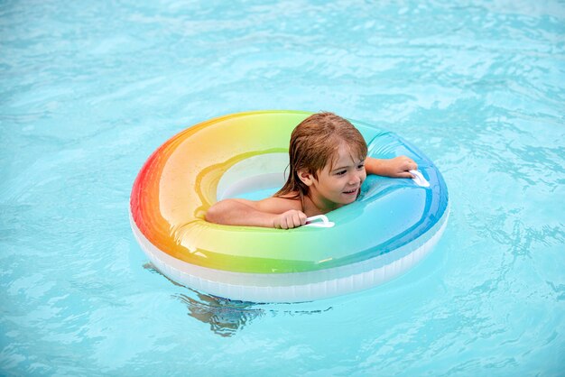 Kinderen zomer zwemmen. Zomer vakantie. Kind bij aquapark. Grappige jongen op opblaasbare rubberen cirkel in zwembad.