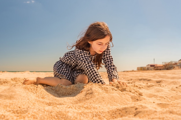 Kinderen zomervakantie. Klein meisje op het strand. Tienermeisje wordt gespeeld op het strand in het zand.