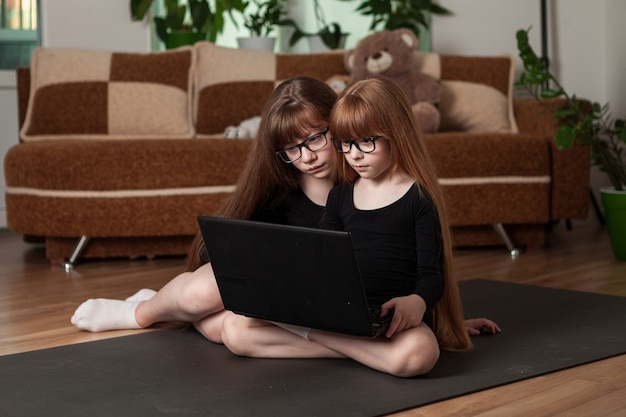 Kinderen, zusjes, trainen thuis op de gymnastiekmat