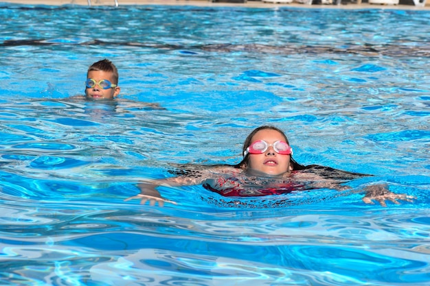 Kinderen zwemmen in het zwembad buiten in het waterpark. vrolijke kinderen actieve watersporten in de zomer. kindervakanties aan zee