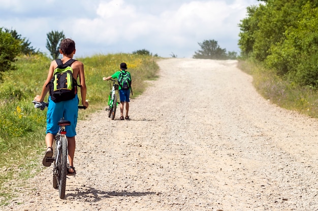 Kinderenjongens die fietsen berijden op een grintweg op een zonnige dag