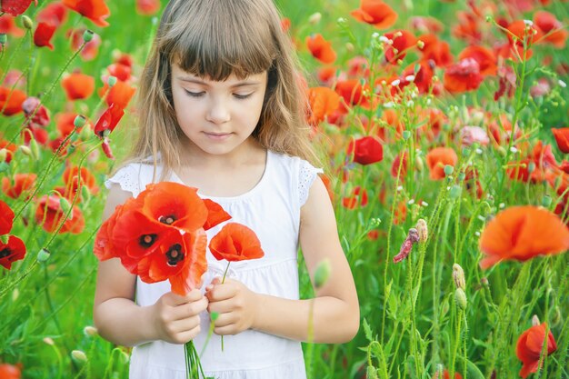 Kinderenmeisje op een gebied met papavers.