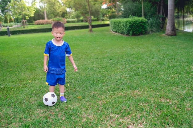 サッカーユニフォームの幼稚園の少年はサッカーをしている