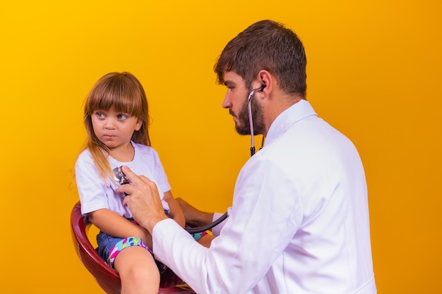 Kindergeneeskunde en regelmatig controleconcept. Attente en aangename blanke arts die de hartslag en ademhaling van het kleine kind controleert met een stethoscoop.