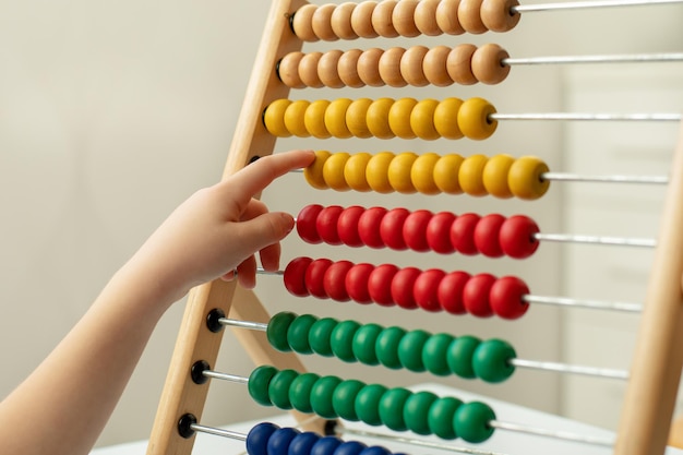 Kinderhand met kleurrijke houten biljetten aan tafel. Montessori-spellen. Begrip onderwijs.