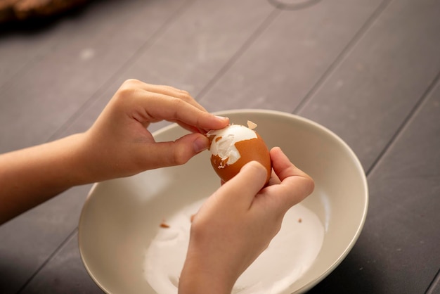 kinderhanden die een gekookt ei pellen in het natuurlijke schot van de keuken