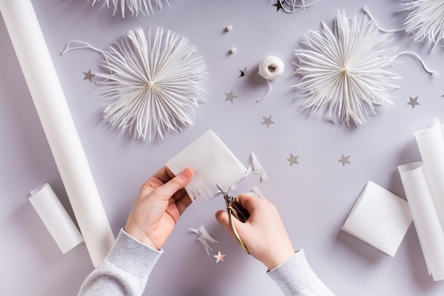 Kinderhanden knippen met een schaar een kerstsneeuwvlok uit papier Handgemaakt decor