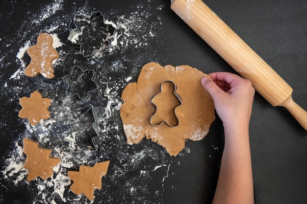 Kinderhanden maken nieuwjaarskoekjes op een houten tafel. koekjes maken met een uitsteekvormpje. nieuwjaar en kerstmis concept.