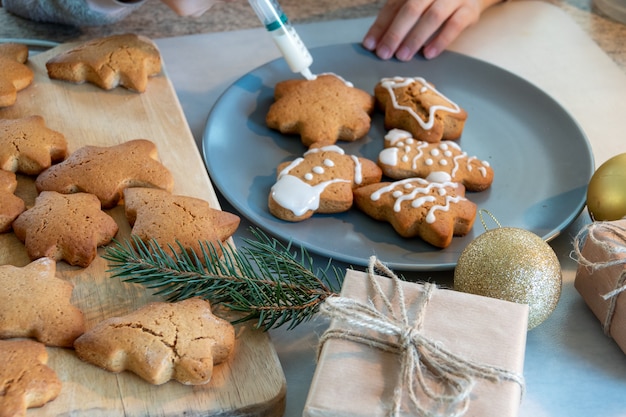 Kinderhanden maken nieuwjaarskoekjes op een houten tafel. Koekjes maken met een uitsteekvormpje. Nieuwjaar en Kerstmis concept.