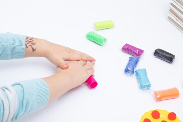 Kinderhanden spelen deeg voor de creativiteit van kinderen. Bordspel voor de ontwikkeling van de fijne motoriek.
