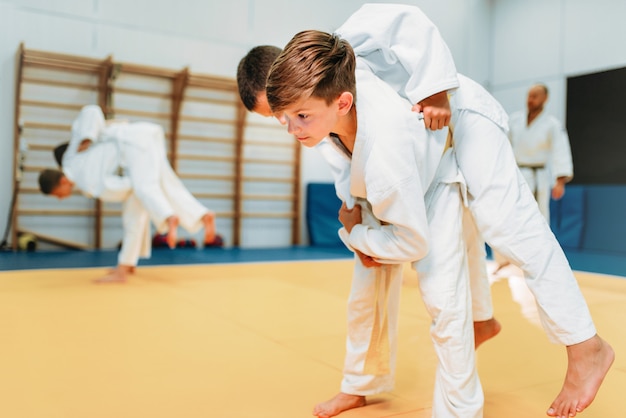 Kinderjudo, jonge vechters op training, zelfverdediging. Kleine jongens in kimono beoefenen krijgskunst