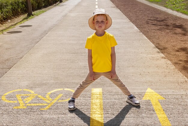 Kinderkleding mockup Een jongen in een geel T-shirt midden op de weg buiten