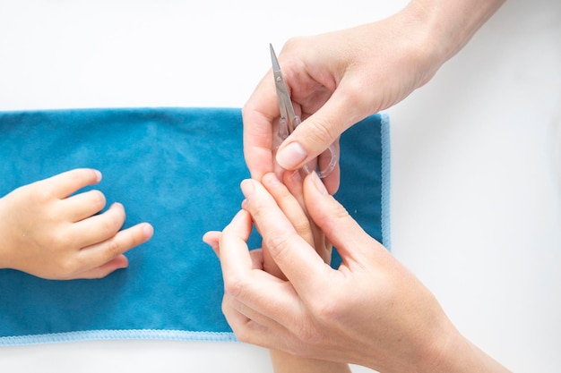 Kindermanicure Vrouwelijke handen knippen nagels op kinderhanden met een manicureschaar Bovenaanzicht plat leggen