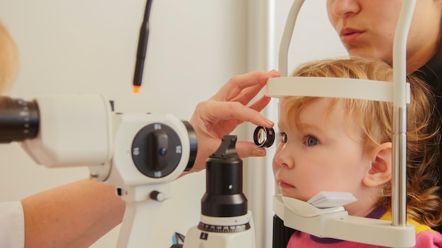 Foto kinderoogheelkunde - arts-optometrist controleert het gezichtsvermogen bij klein meisje, telefoto