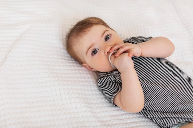 Kinderopvang concept Schattige kleine baby liggend op bed meisje draagt bodysuit en bevochtigt de fopspeen kopie ruimte