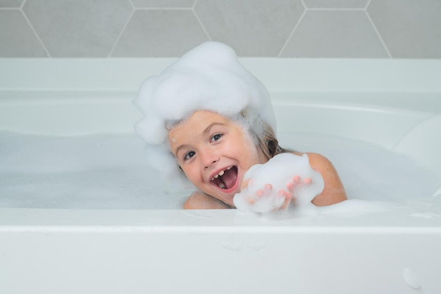Kindershampoo kind badend in een bad met schuim grappig kindergezicht badend in het bad