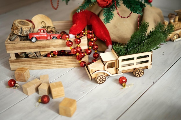 Kinderspeelgoed en geschenken op de vloer onder de kerstboom Ansichtkaart met tilke rustieke Houten vrachtwagen kerstmuts en houten cupcakes
