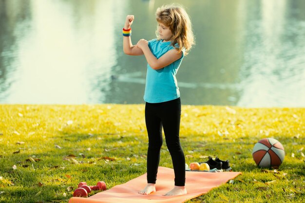 Kindersportman met halter in de sportfitness van het lentepark voor energie, de gezondheid van kinderen, training van gelukkige s