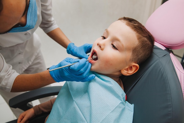 Kindertandarts behandelt kindercariës en mondholte van jongen die in tandartsstoel zit tijdens regelmatige medische controle