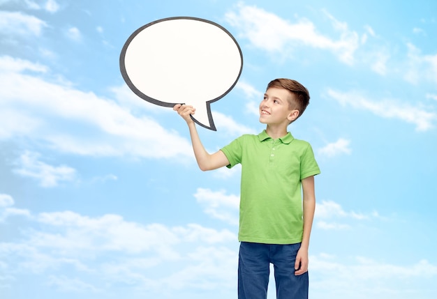 kindertijd, communicatie, reclame en mensenconcept - gelukkige lachende jongen in groen polo t-shirt met lege witte tekst zeepbel banner over blauwe lucht en wolken achtergrond