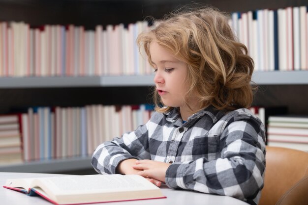 Kindertijd en onderwijsconcept Kind leest een boek in een schoolbibliotheek Schooljongen onderwijsconcept