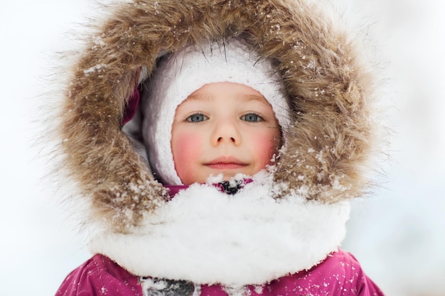 kindertijd, mode, seizoen en mensenconcept - gezicht van een gelukkig klein kind of meisje in winterkleren