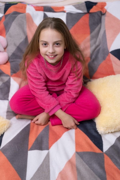 Foto kindertijd van een tienermeisje dat zit te ontspannen kindertiijd van een tiendermeisje die zich ontspant in het bed kindertijd von tienermeesje dat zich ontspannt in de slaapkamer kindertijd of tienermeissie die zich relaxeert in een pyjama