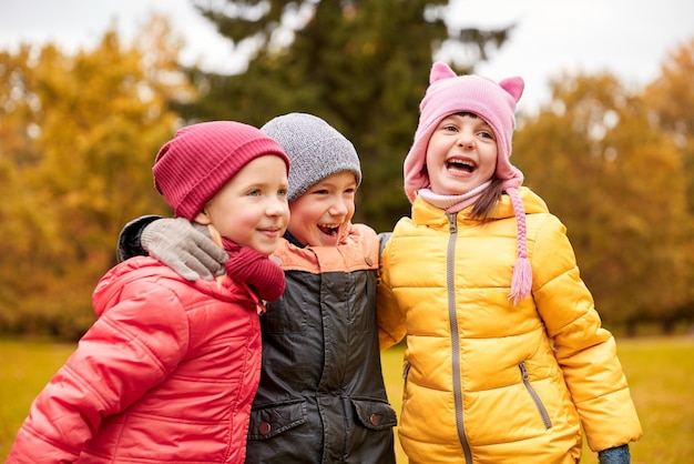 kindertijd, vrije tijd, vriendschap en mensenconcept - groep gelukkige kinderen knuffelen en lachen in het herfstpark