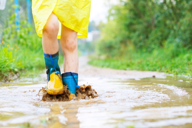 Kindervoeten in een rubberen laars in een plas