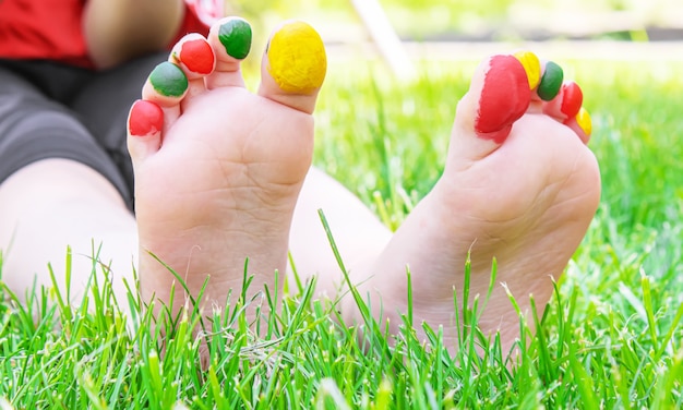 Foto kindervoeten met een patroon van verfglimlach op het groene gras. selectieve aandacht. natuur.