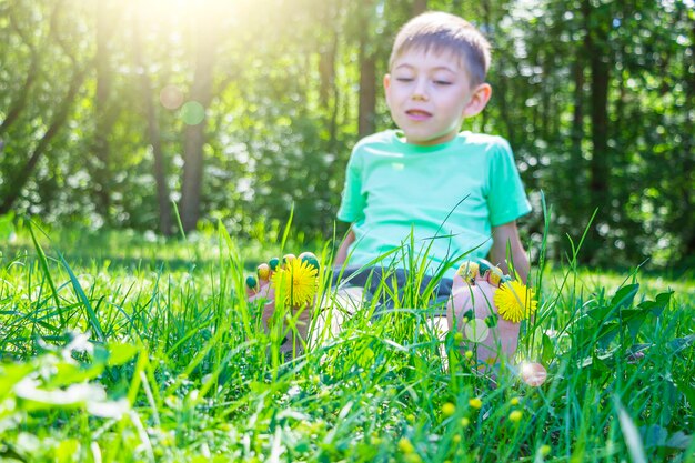 Kindervoeten met paardebloembloem op groen gras in zonnige zomerdag