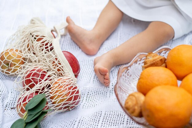 Kindervoeten zijn bloot op een picknick een voering waarop fruit sinaasappels en appels zijn