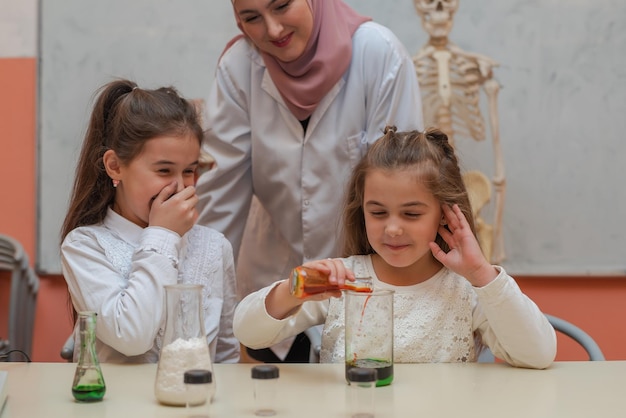 Kinderwetenschappers met een vrouwelijke moslimleraar doen scheikunde-experimenten in het schoollaboratorium.
