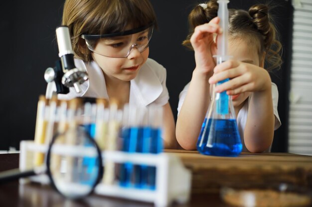 Kinderwetenschappers Schoolkinderen in het laboratorium voeren experimenten uit Jongens- en meisjesexperimenten met een microscoop