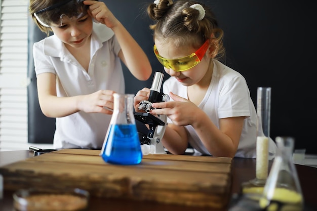 Kinderwetenschappers Schoolkinderen in het laboratorium voeren experimenten uit Jongens- en meisjesexperimenten met een microscoop